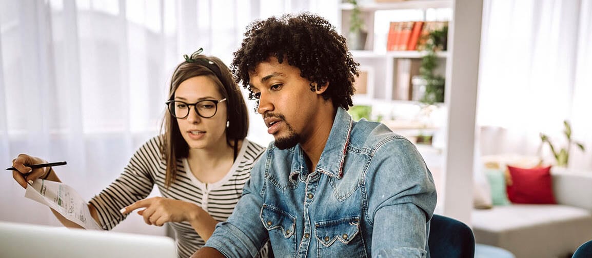 A couple sitting on a dining table with a laptop and discussing about loan to value ratio