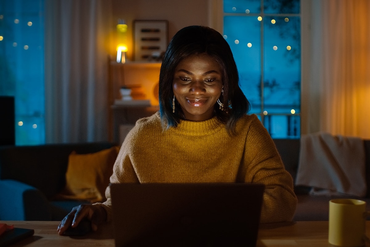 Someone working on a laptop at night with a coffee cup beside them