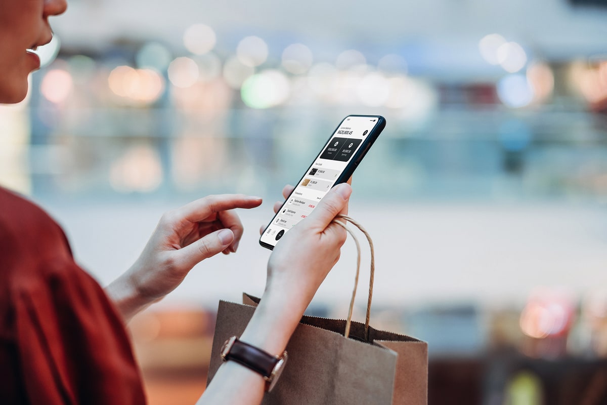 A professional image of a person using a mobile banking app to view multiple savings accounts, with labeled goals like “Emergency Fund” and “Vacation Savings.”