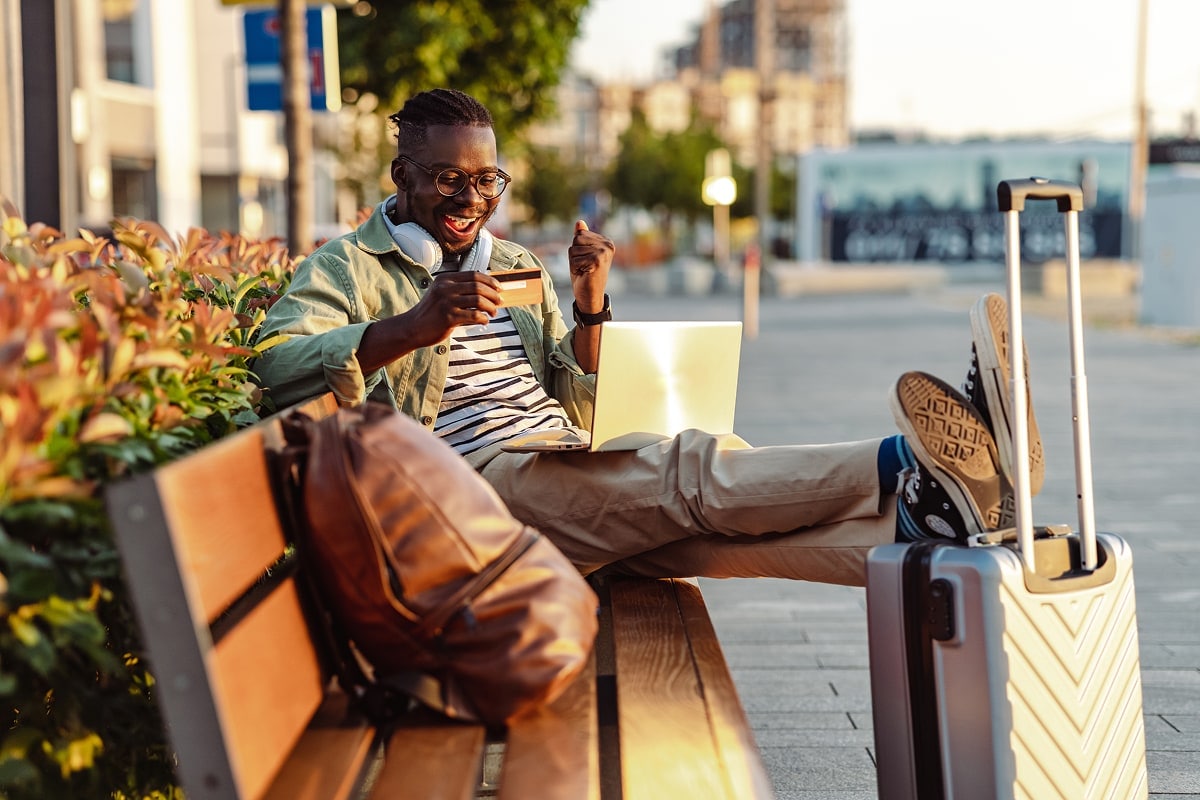 An image of a traveller holding a credit card with excitement.