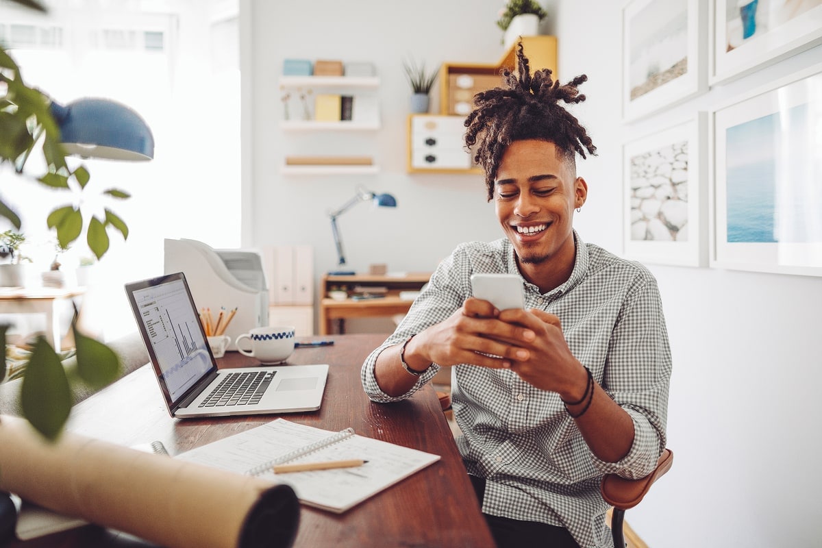 A professional image of a person using a mobile banking app on their smartphone, with a coffee shop or home setting in the background. 