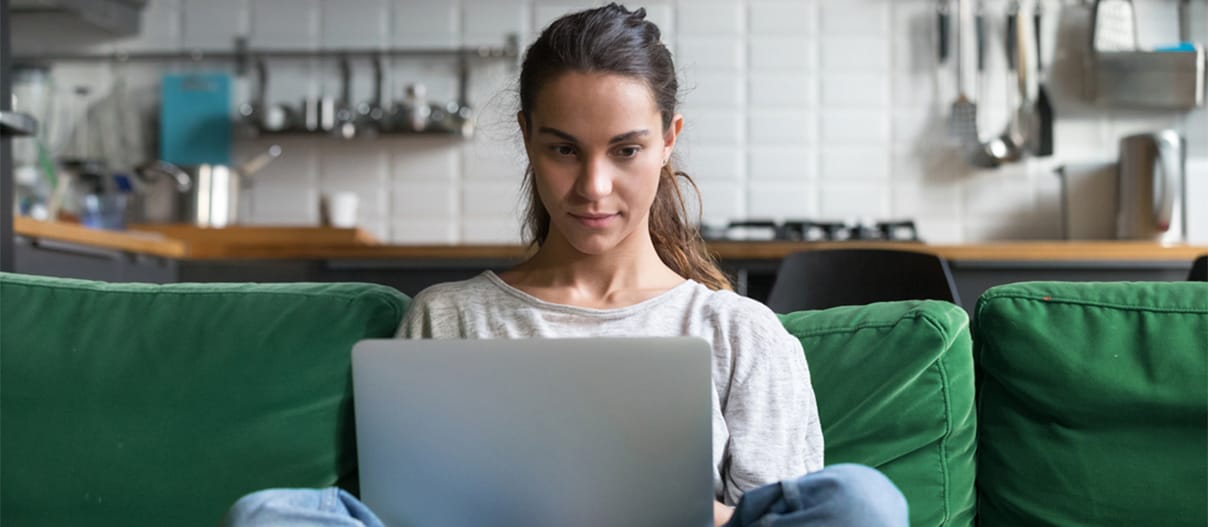 A woman sitting on a couch working on her laptop