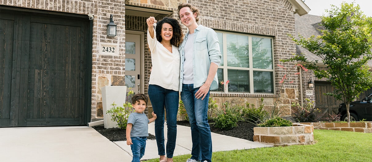 Family with keys standing outside a home