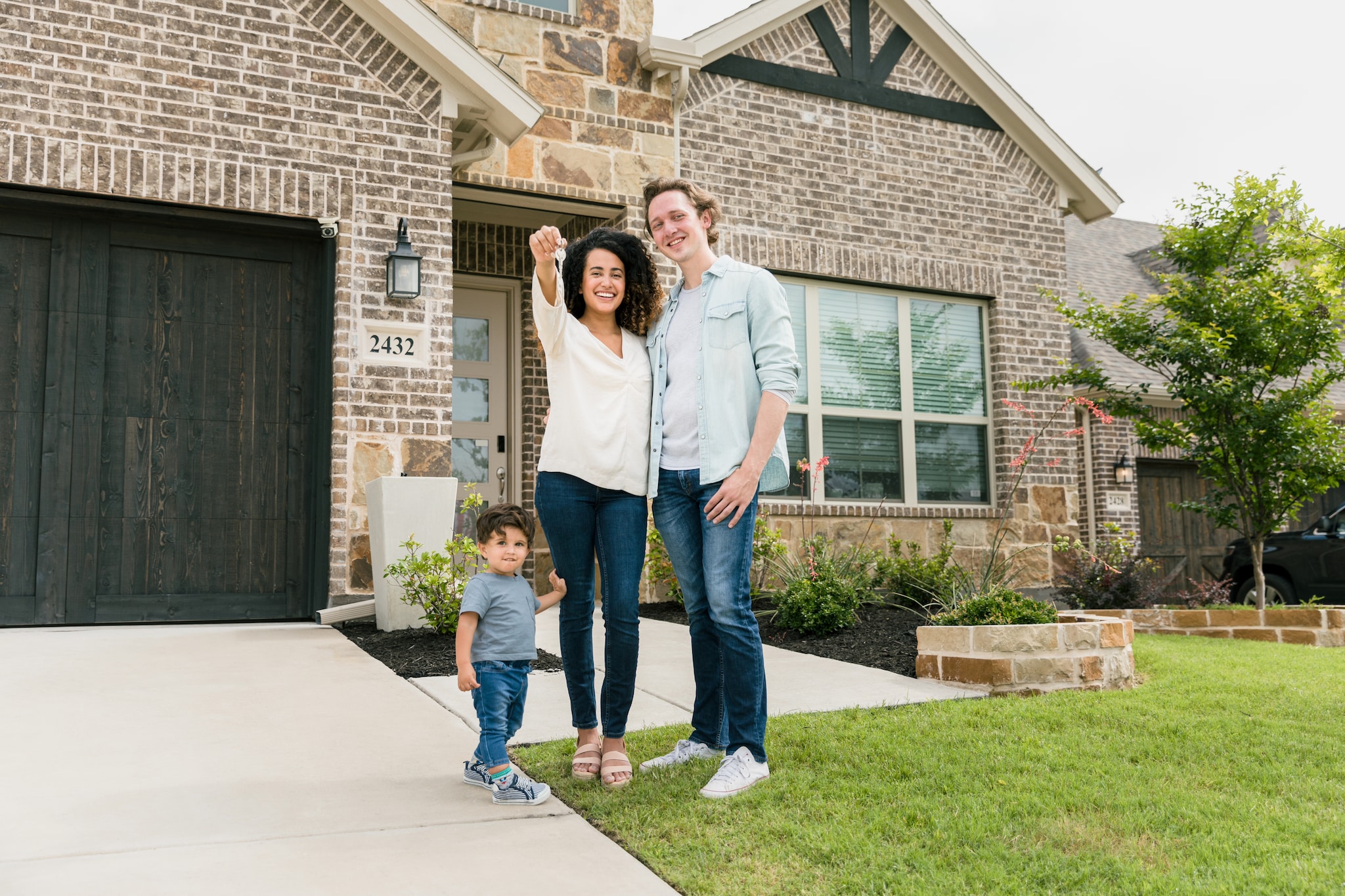 Family with keys standing outside a home