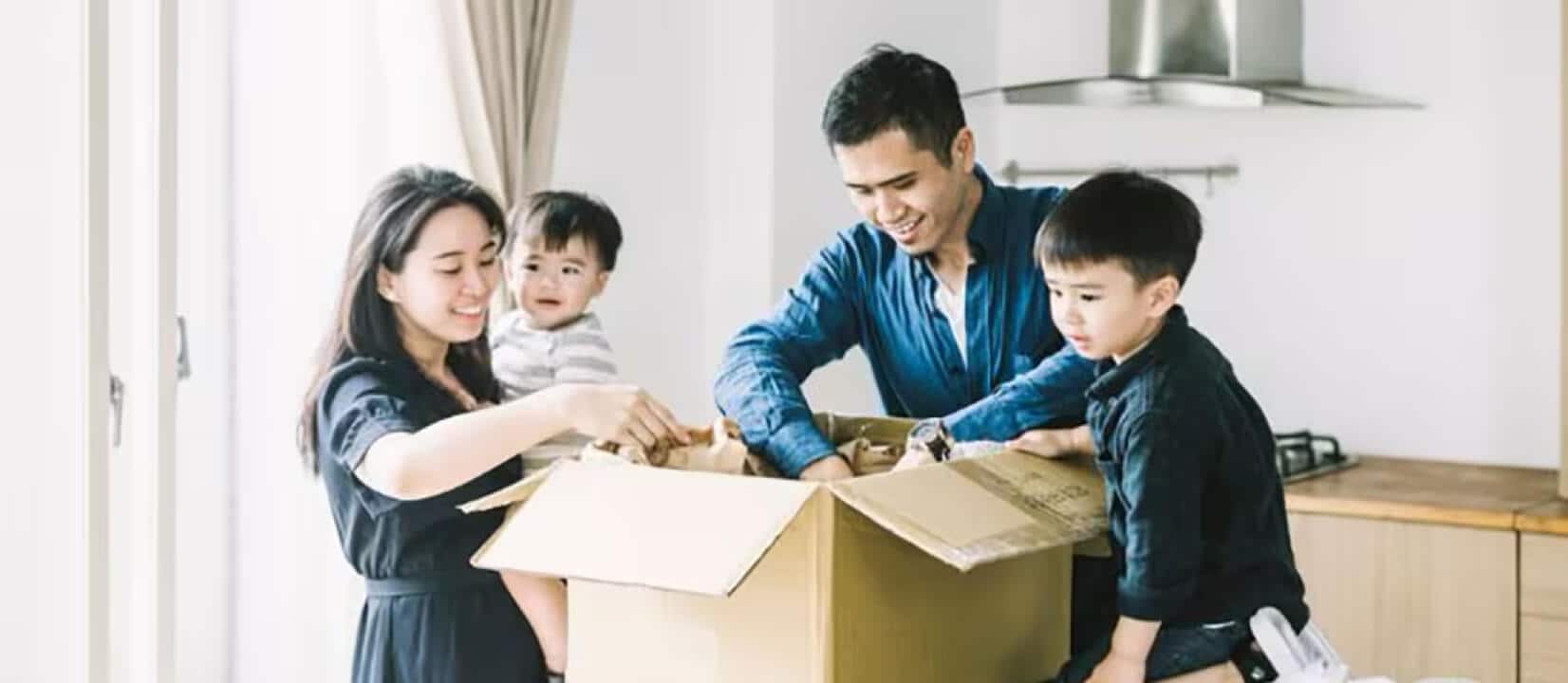 A family unpacks a box in the kitchen of their new home