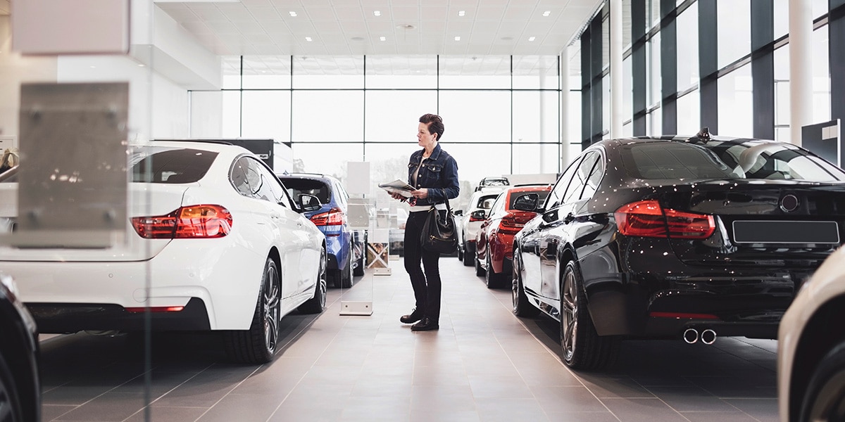 A person looking at new cars at a dealership.