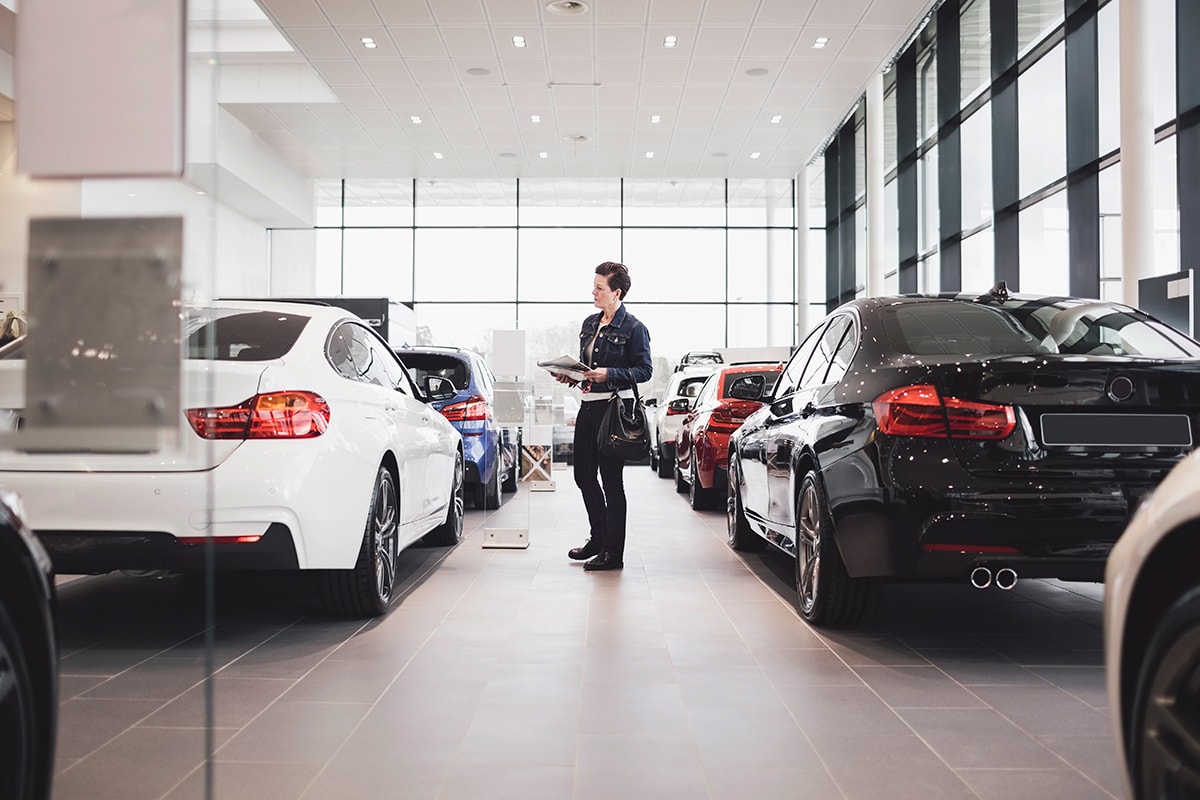 A person looking at new cars at a dealership.