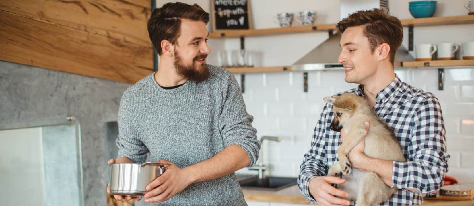 Two men are carrying boxes into a new home, symbolizing the excitement of first-time home buyers and potential tax credits.