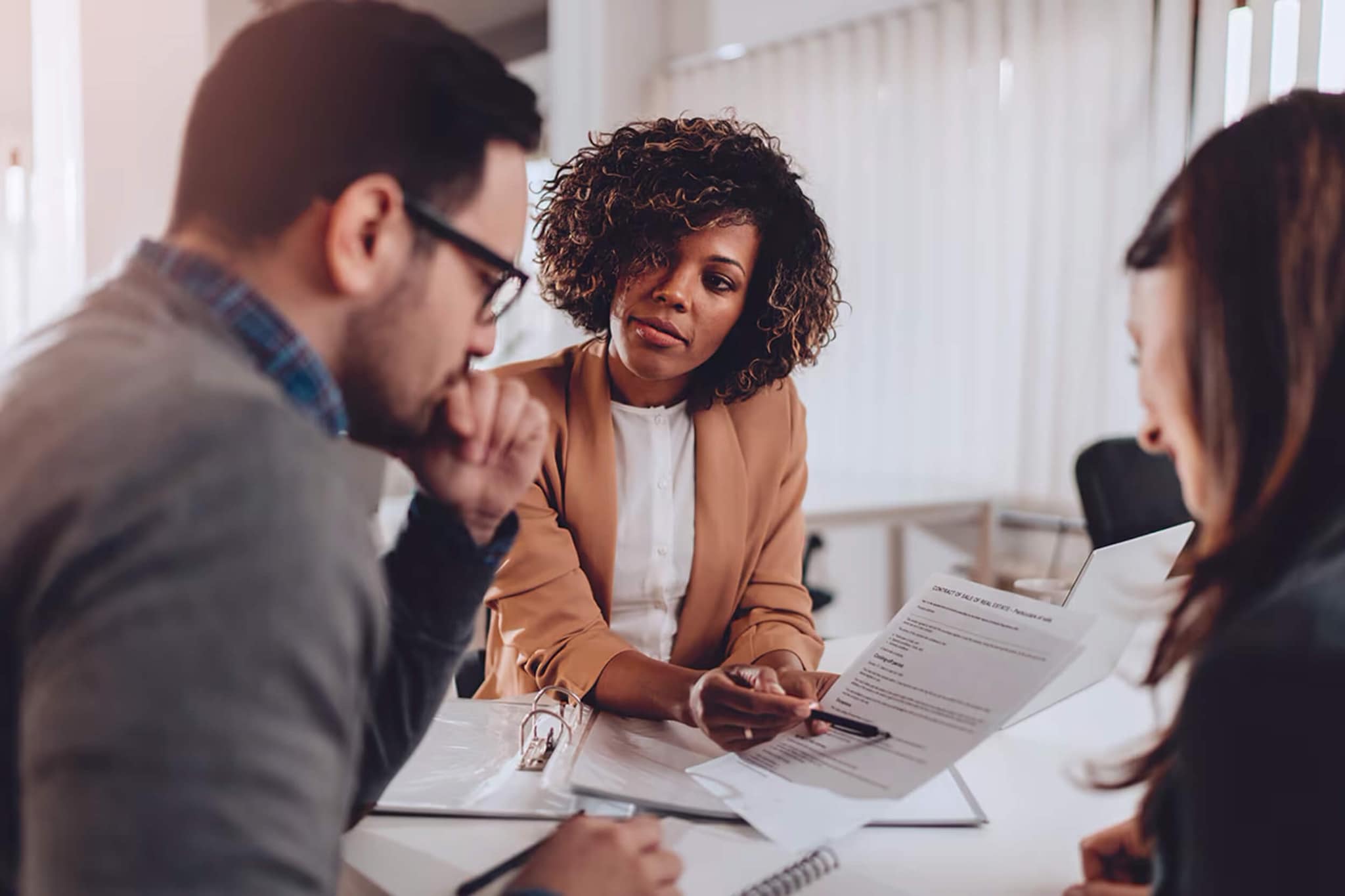 A woman and two men engage in a discussion during a meeting about new rules for inherited IRAs and 401(k)s.