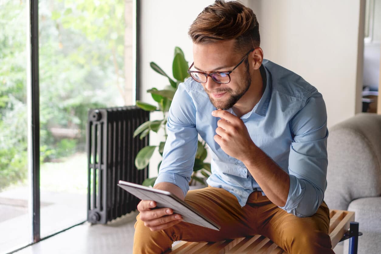 Man is sitting in a room, looking at a tablet