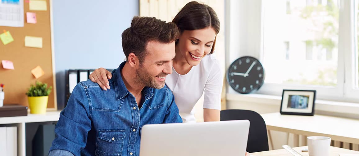 A couple reviewing paperwork together while utilizing a laptop.