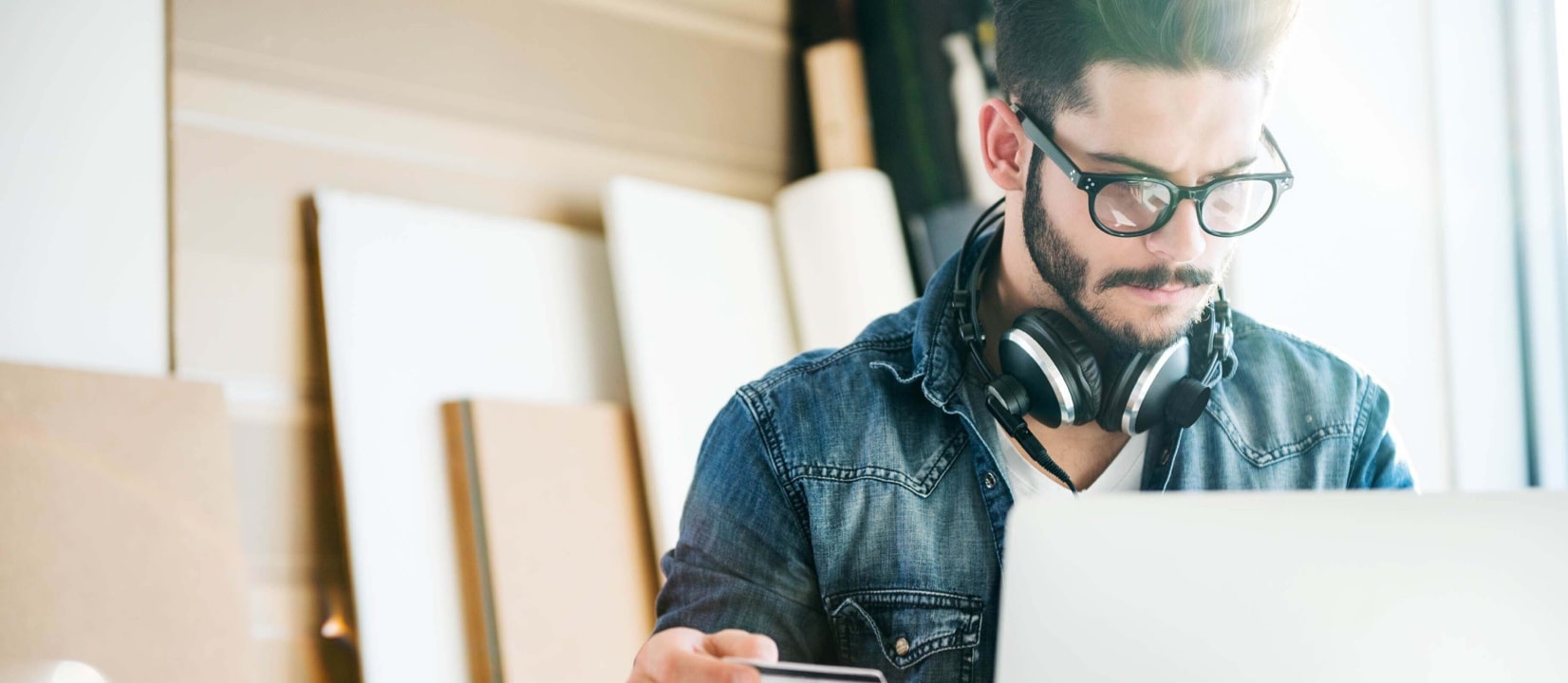 Man is looking at a laptop and holding a credit card in a renovation room