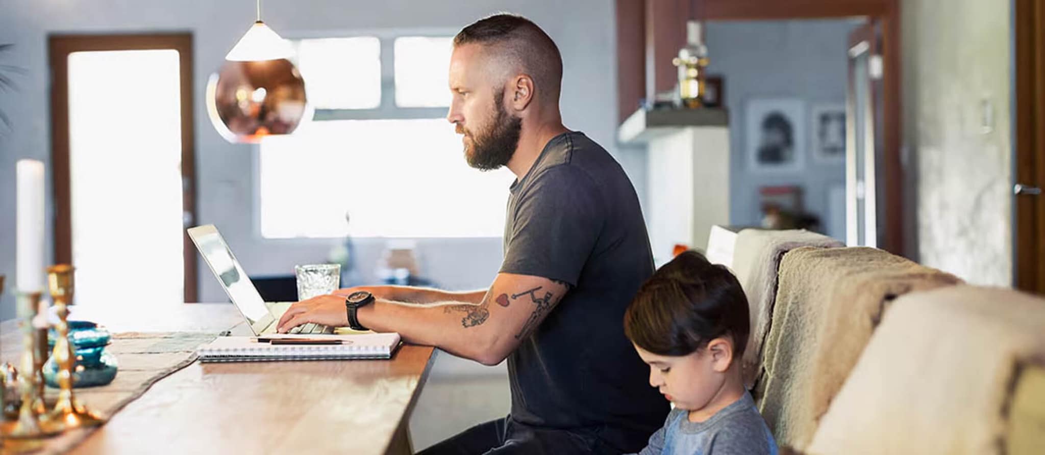 A man and a child are at a table with a laptop, representing a bonding experience through technology and education.