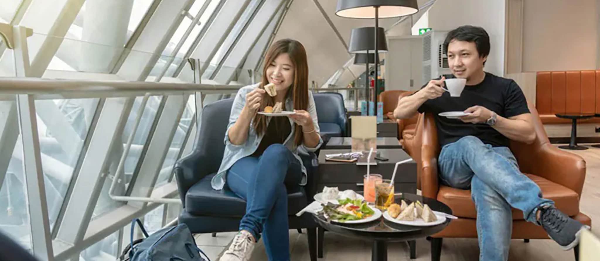 Two individuals seated in chairs, enjoying a meal and sipping coffee, showcasing a moment of leisure with a premium travel credit card.