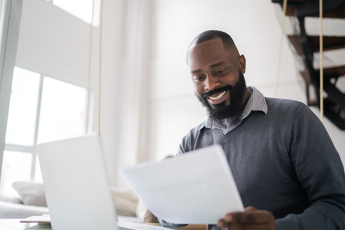 Someone smiling at a desk, looking at a piece of paper