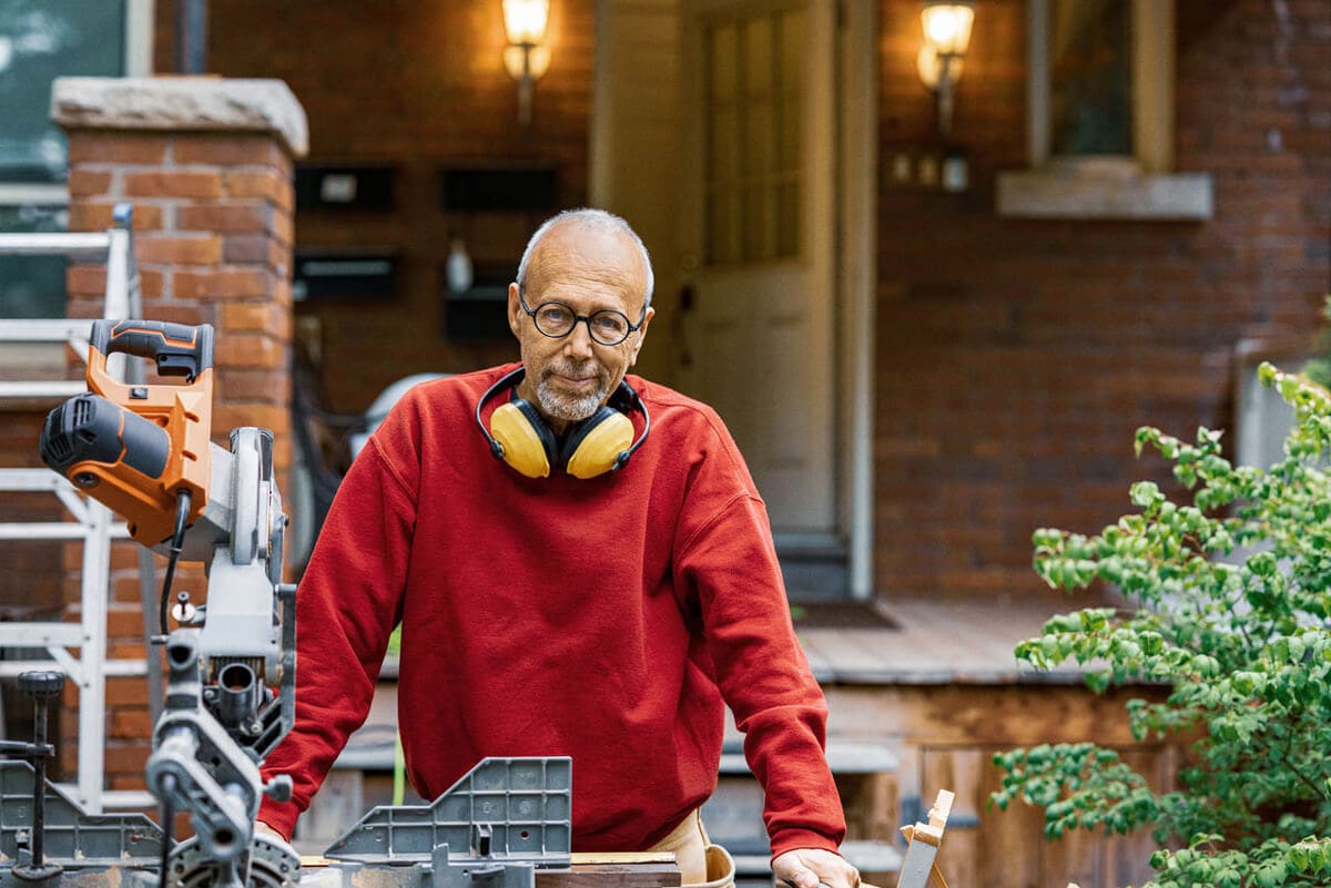 A man standing with equipments on the front porch.