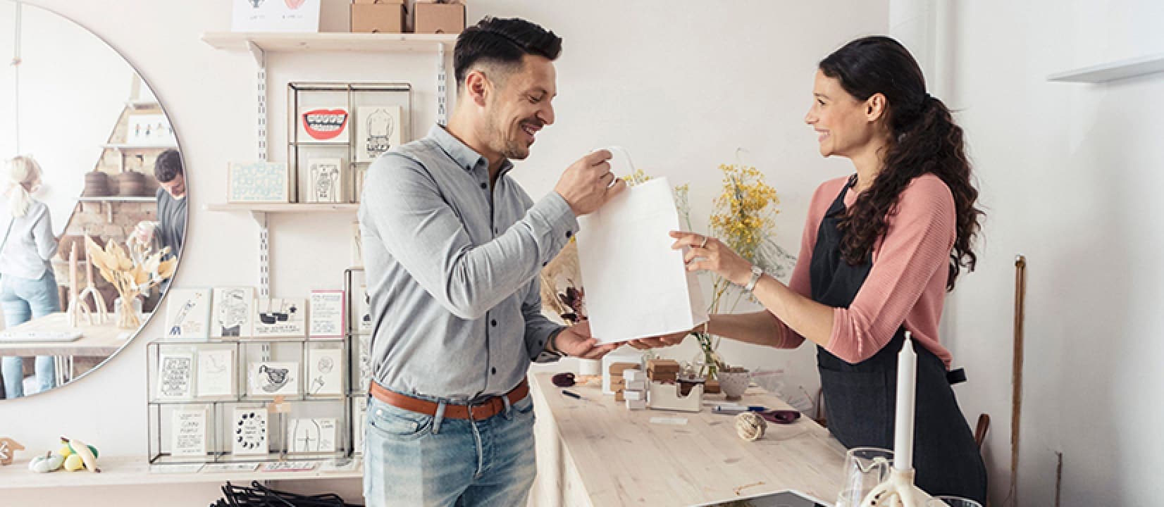 A photo of a person at a department store returns counter with a shopping bag.