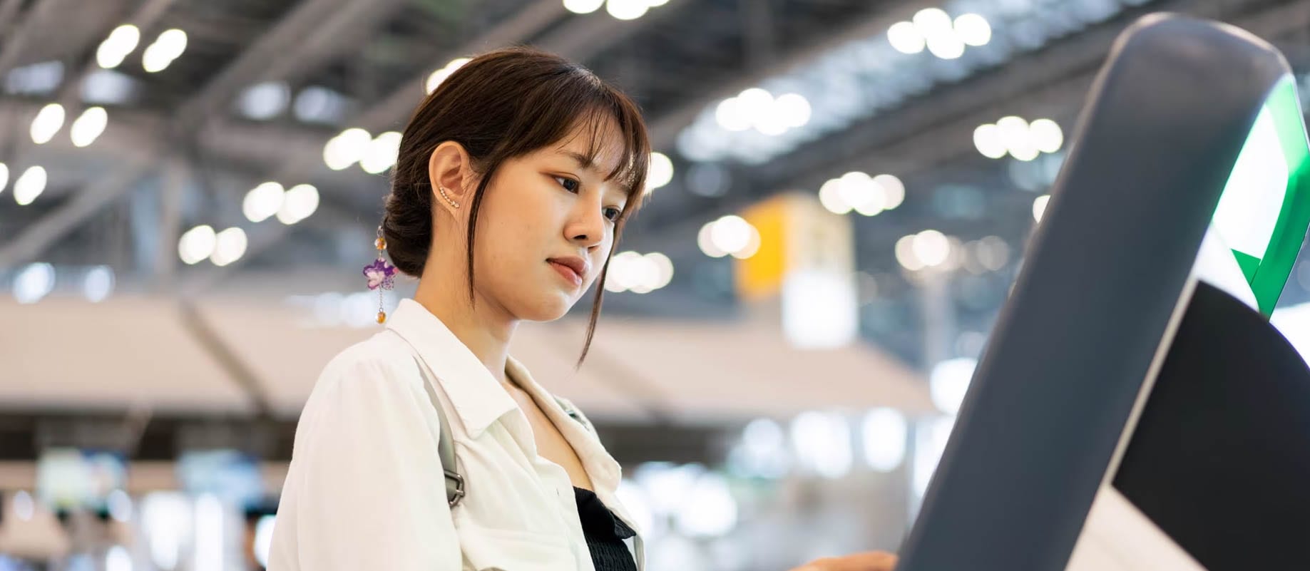 Woman is in the airport at the self-checkout kiosk