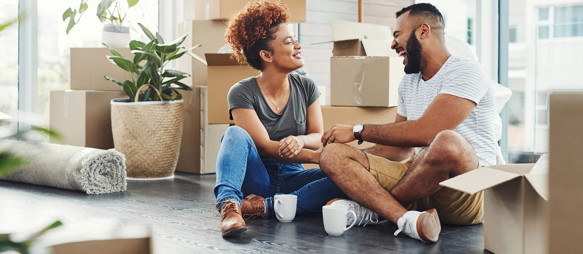 A couple sits on the floor of their new home, contemplating whether to rent or buy their next property.