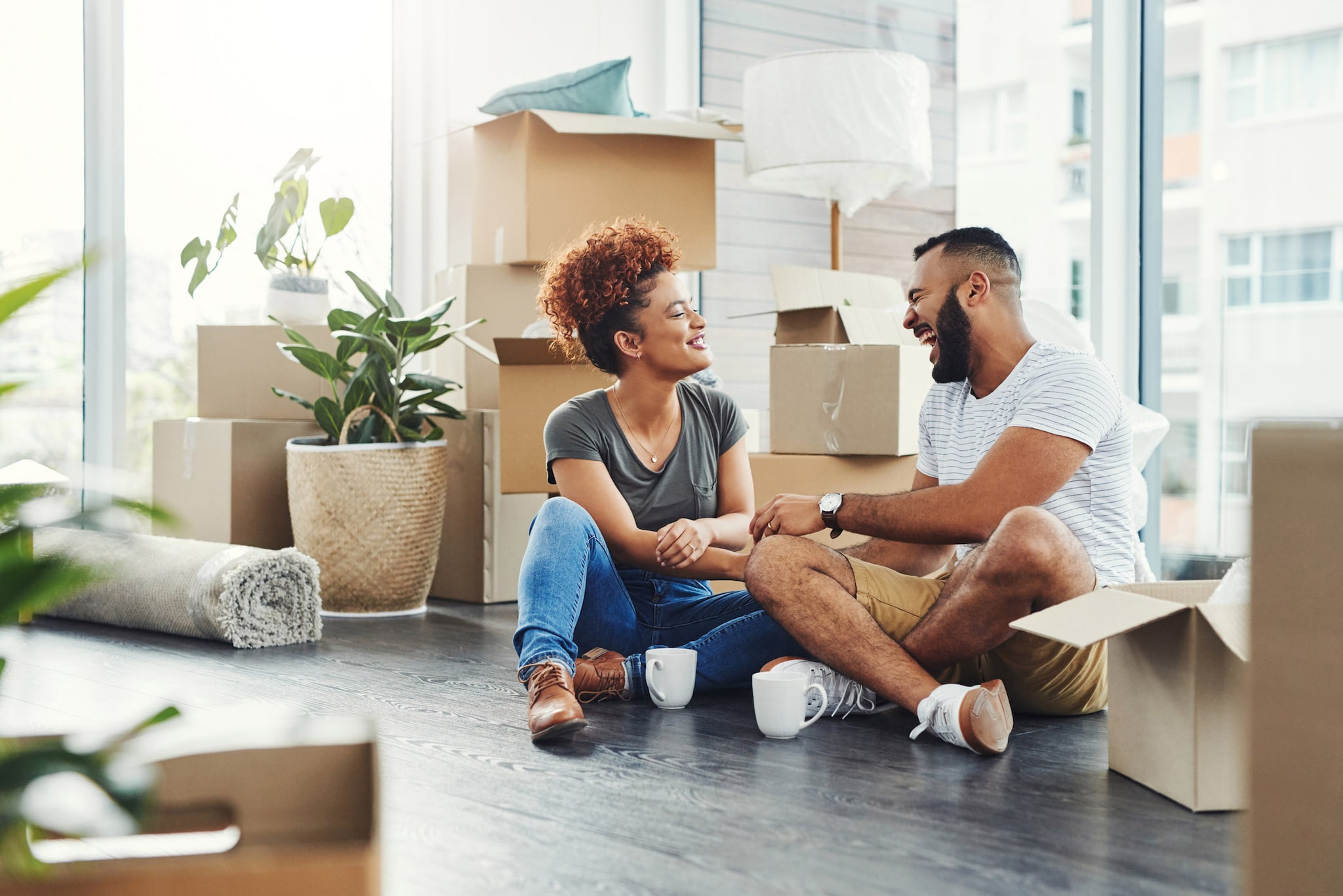 A couple sits on the floor of their new home, contemplating whether to rent or buy their next property.