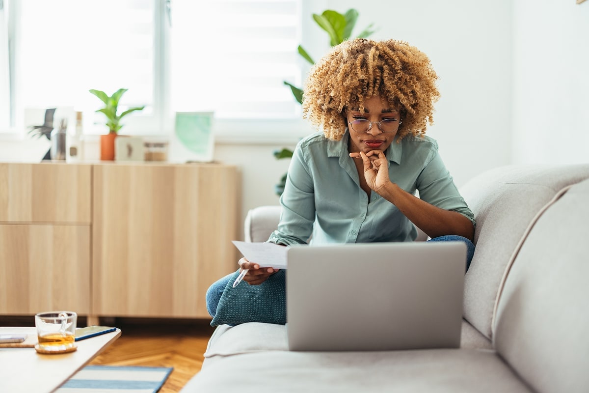 A professional image of a person sitting at a desk with their ID, utility bill, and laptop.