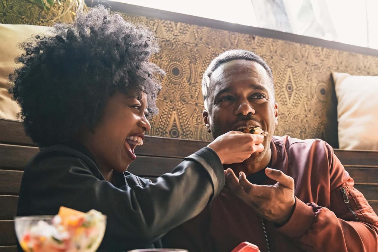 A young couple enjoying a meal together at a restaurant, sharing a moment while saving money on dining out.