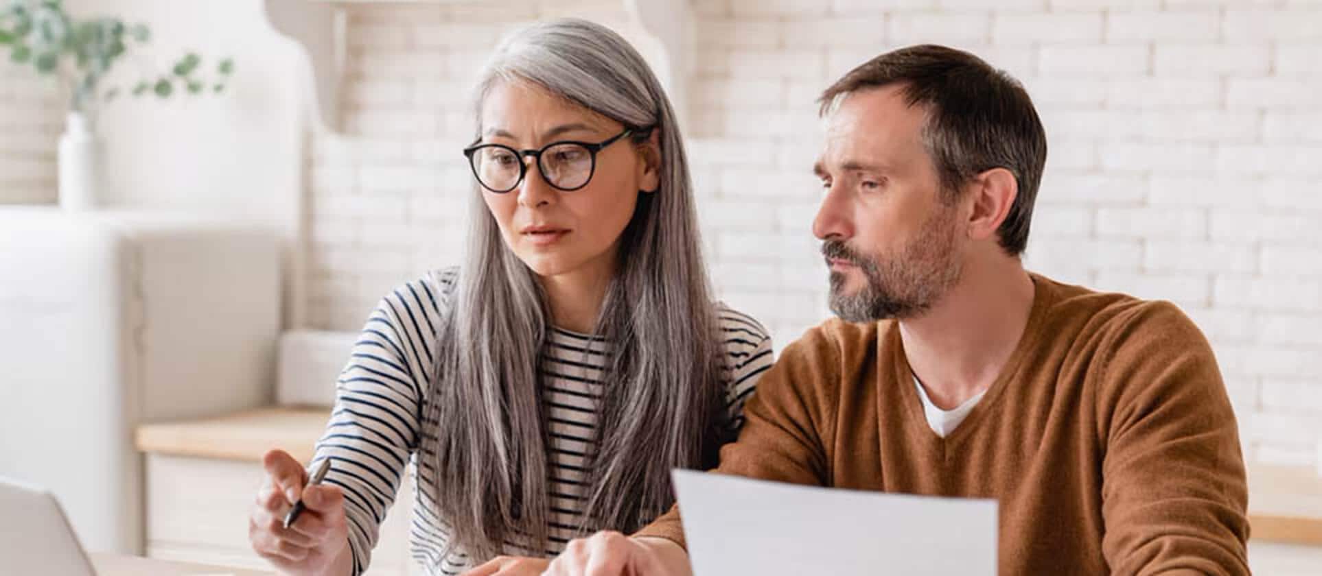 An older couple reviews paperwork together at a table, discussing their retirement spending plan.