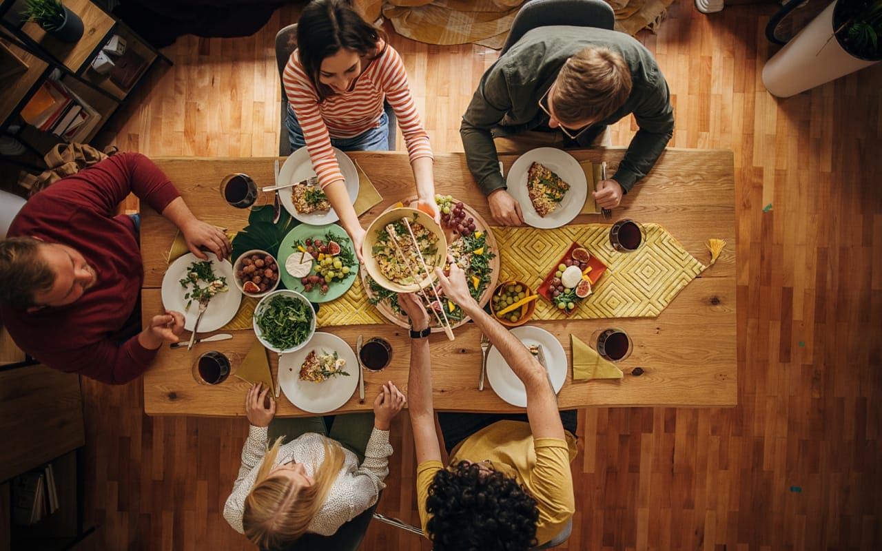 A lifestyle photo of a group of friends dining at a restaurant, laughing and enjoying their meal, with a bill and credit card visible on the table. 