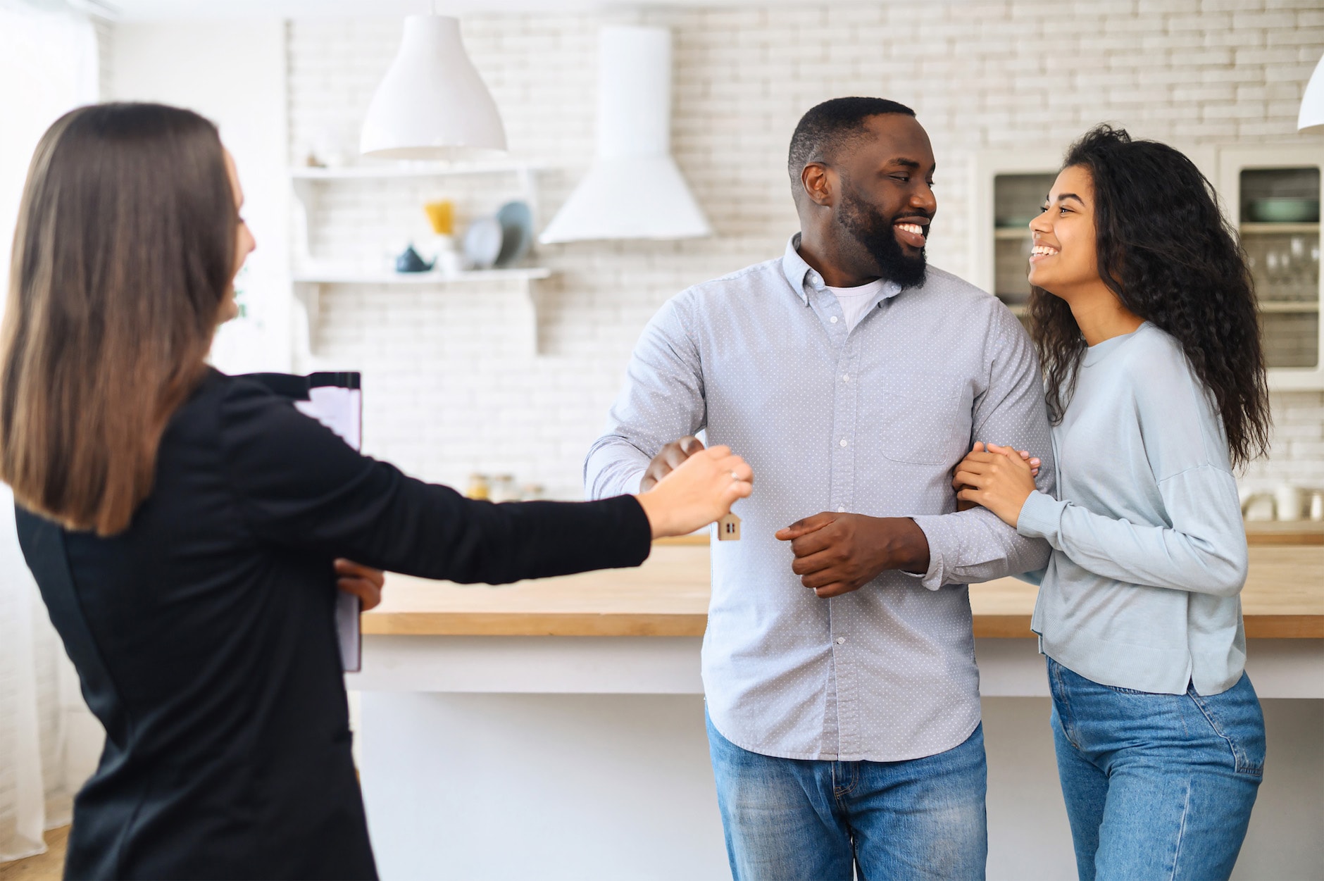 Couple is smiling and getting a key to a house from an agent