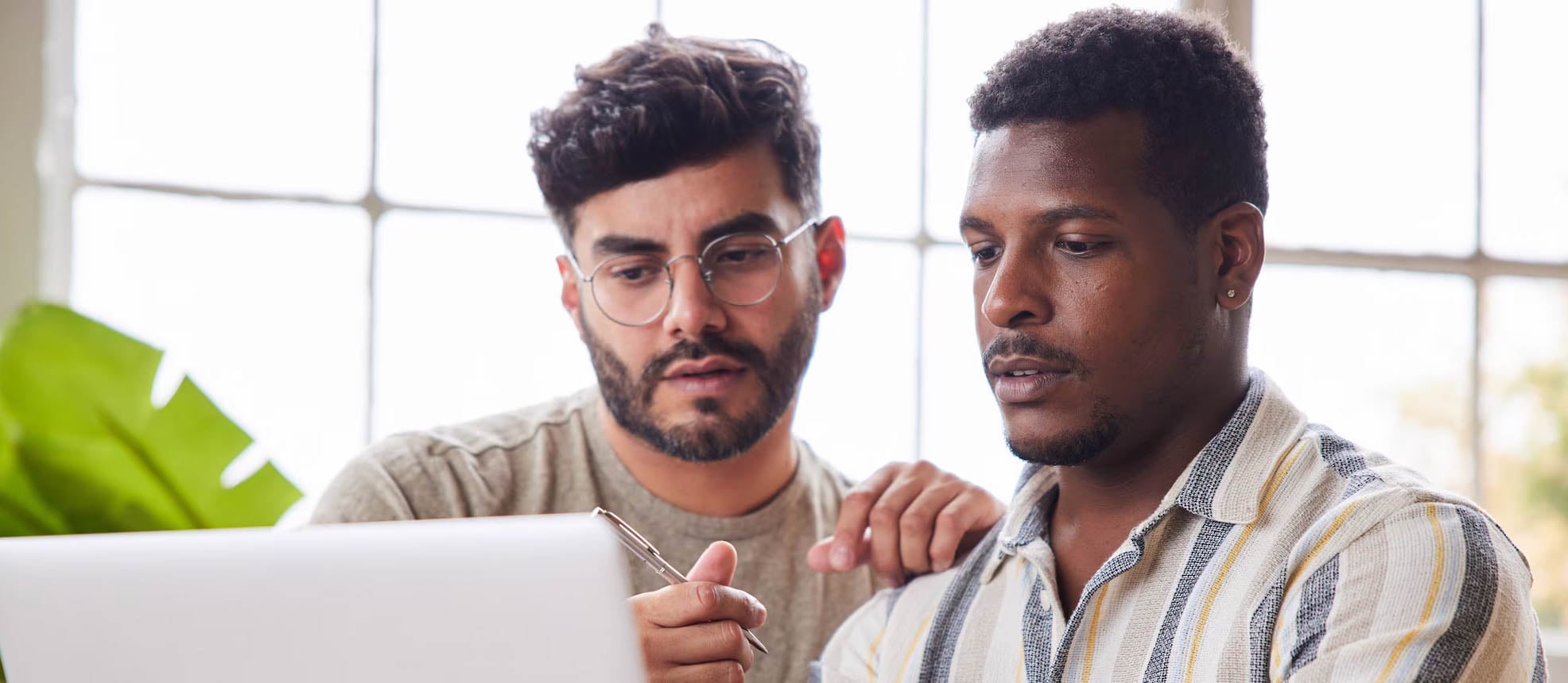 Two men are looking at a laptop, discussing the signs of identity theft.