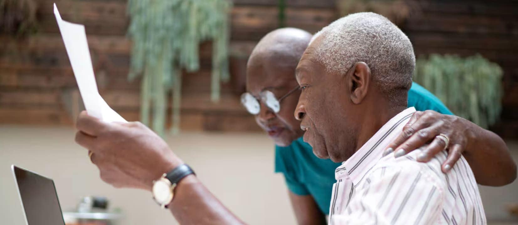 An elderly couple analyzing a document on a laptop, engaged in a discussion about retirement investment choices.