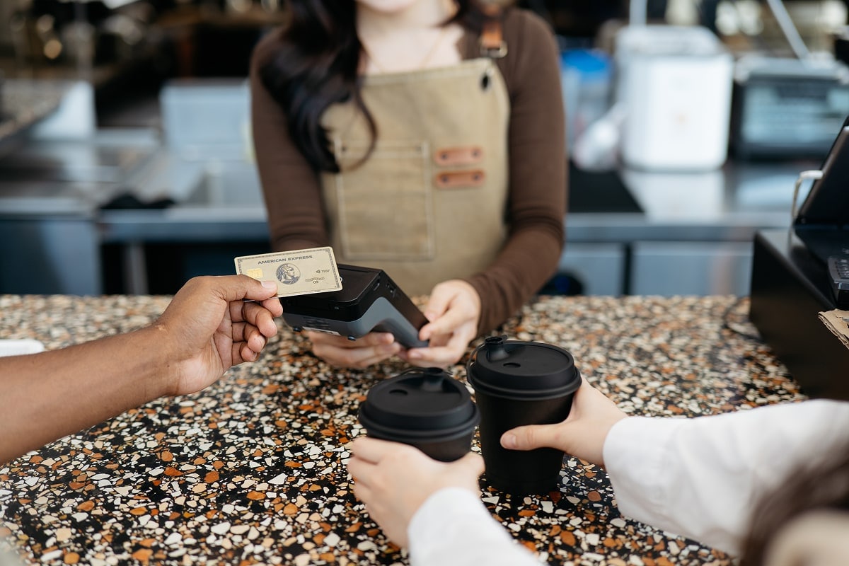 A professional image of a traveler using a credit card at a café in a foreign city, with a map and passport on the table. 