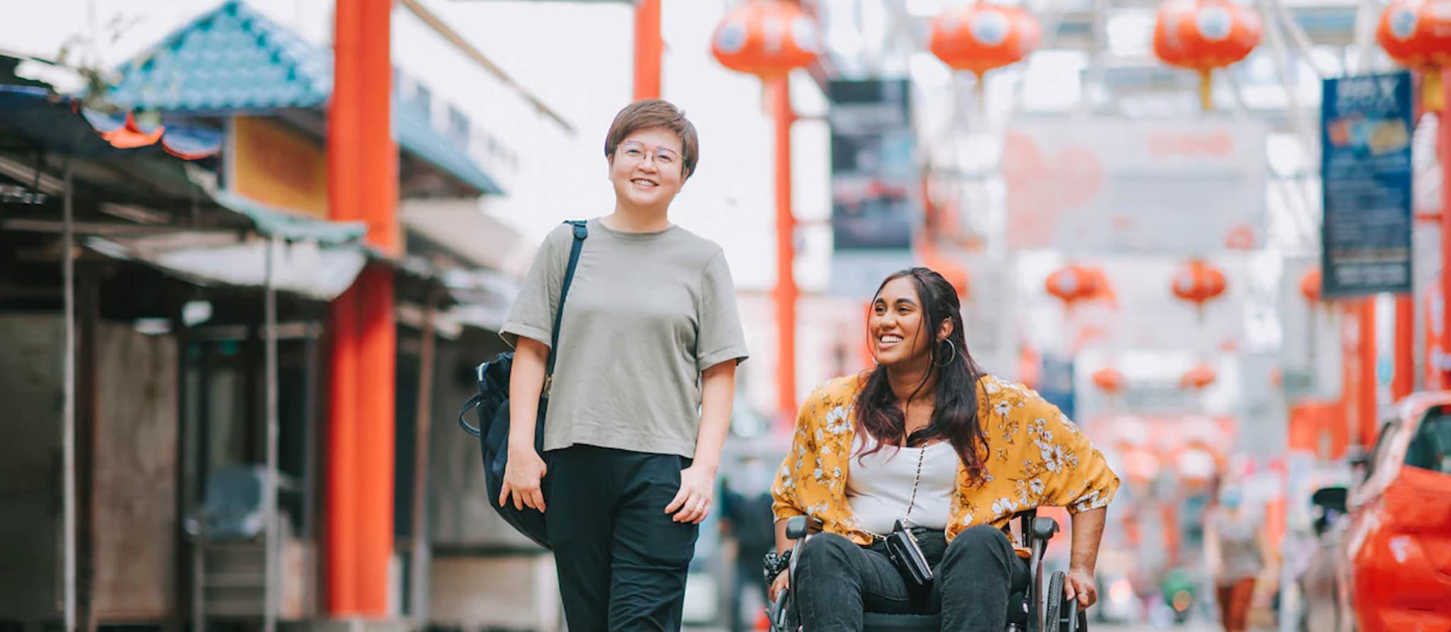 Two women traveling together happily, one with a physical disability