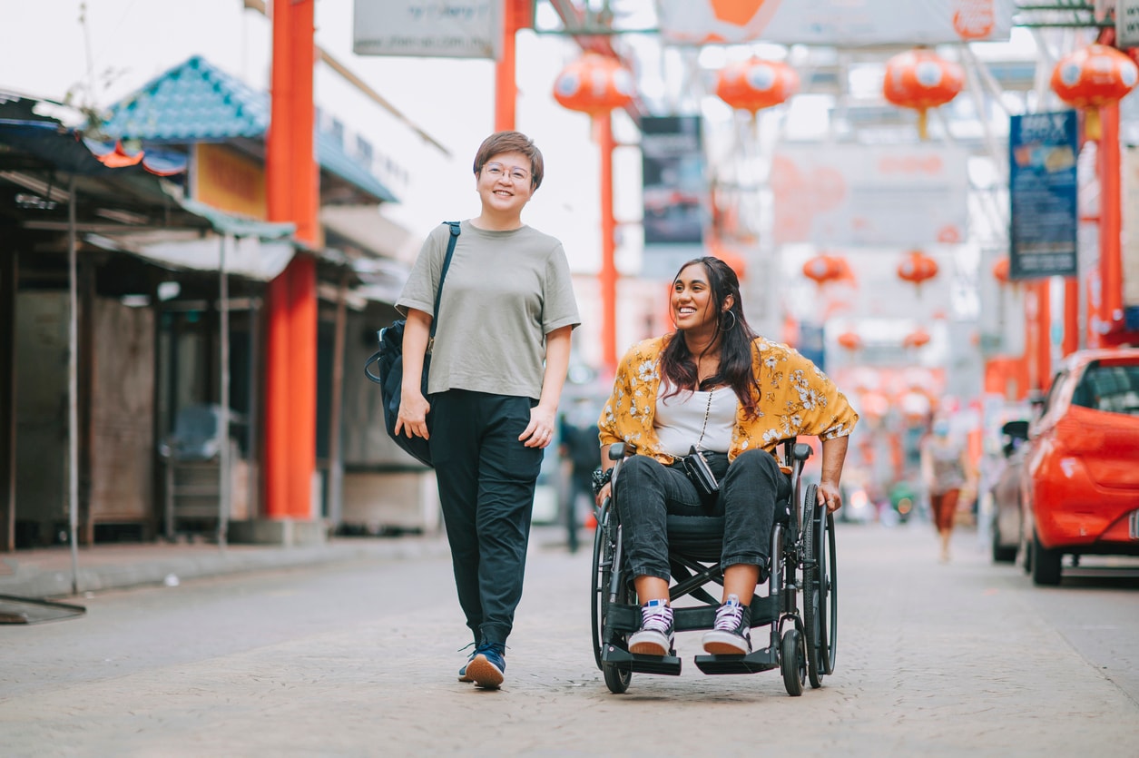 Two women traveling together happily, one with a physical disability