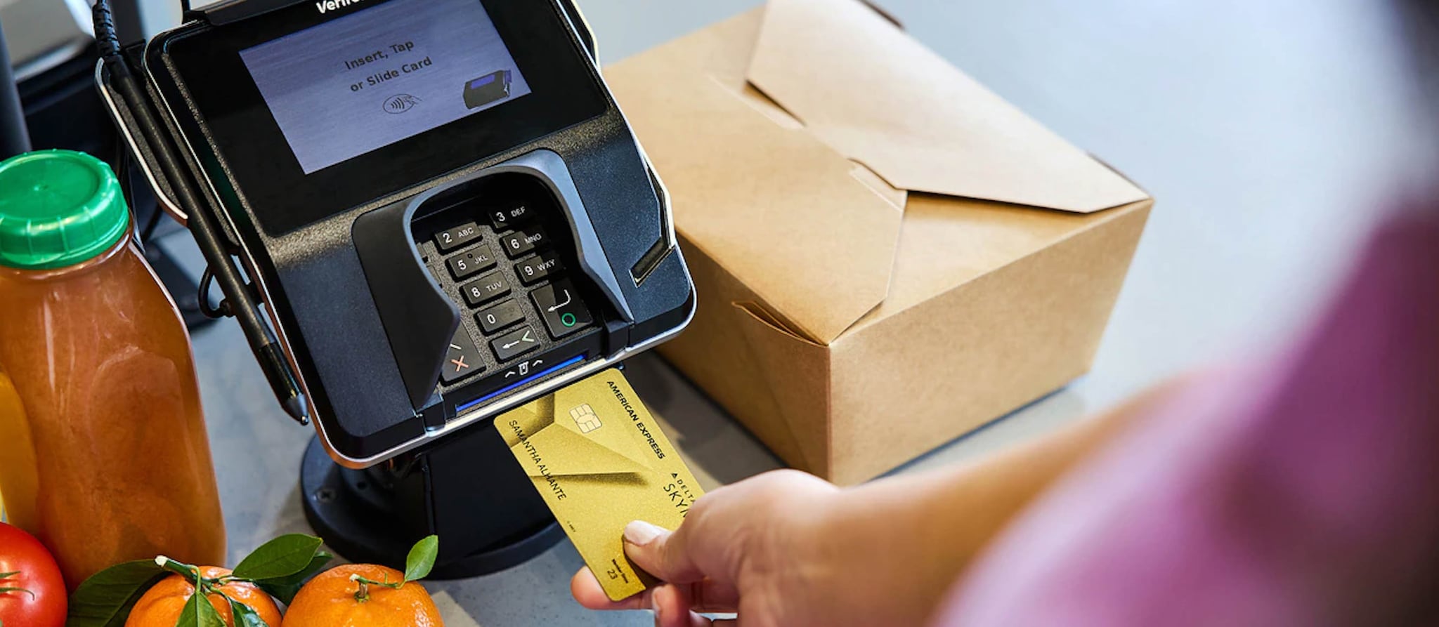 Person is paying at the register for a grocery with the American Express Gold Delta Credit Card