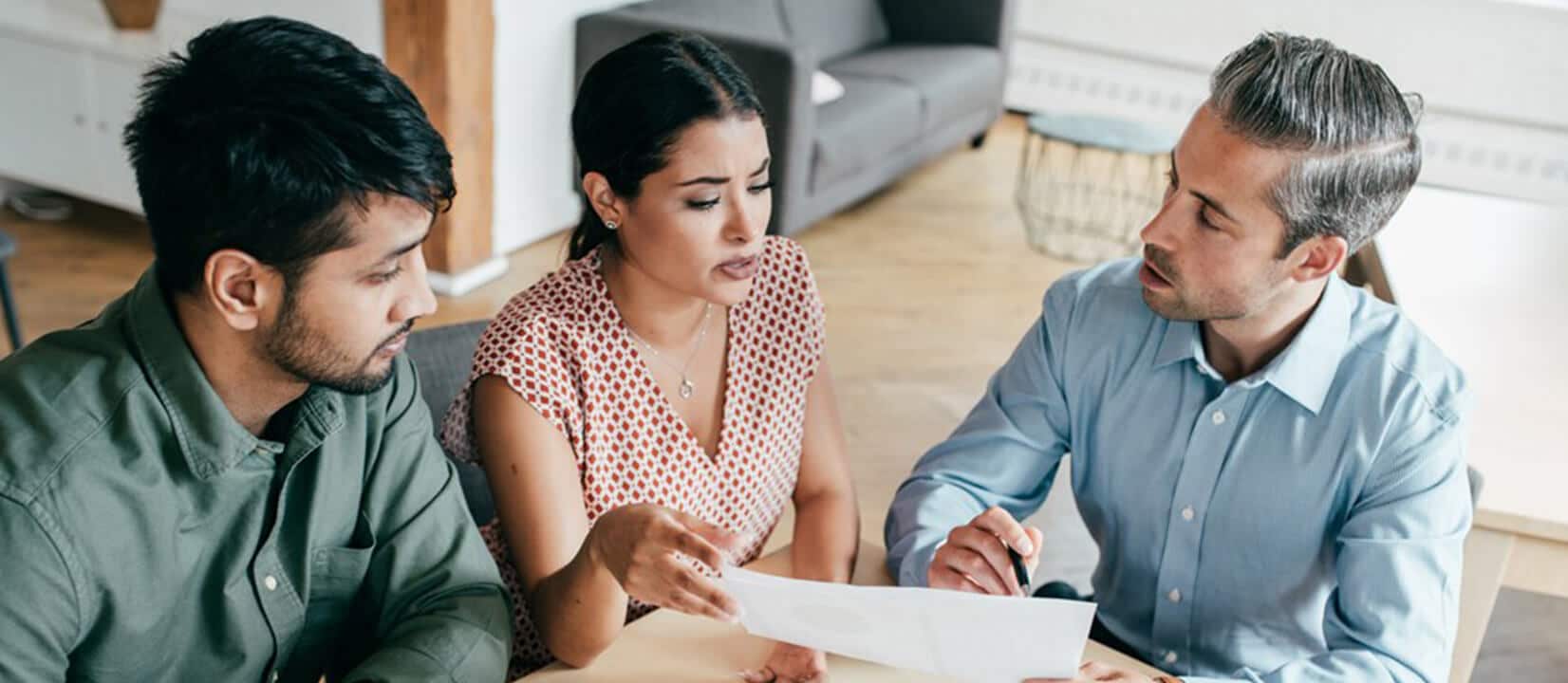 Three individuals seated at a table, reviewing papers related to four different types of mutual funds.
