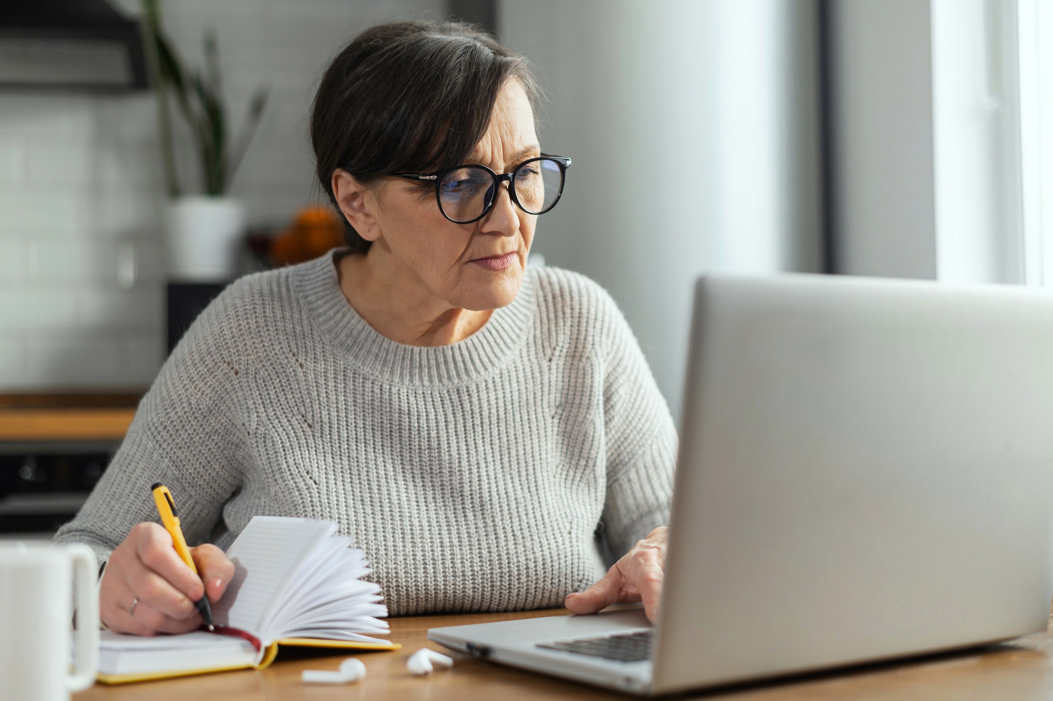 A woman is checking what unsecured debt is on her laptop and taking notes