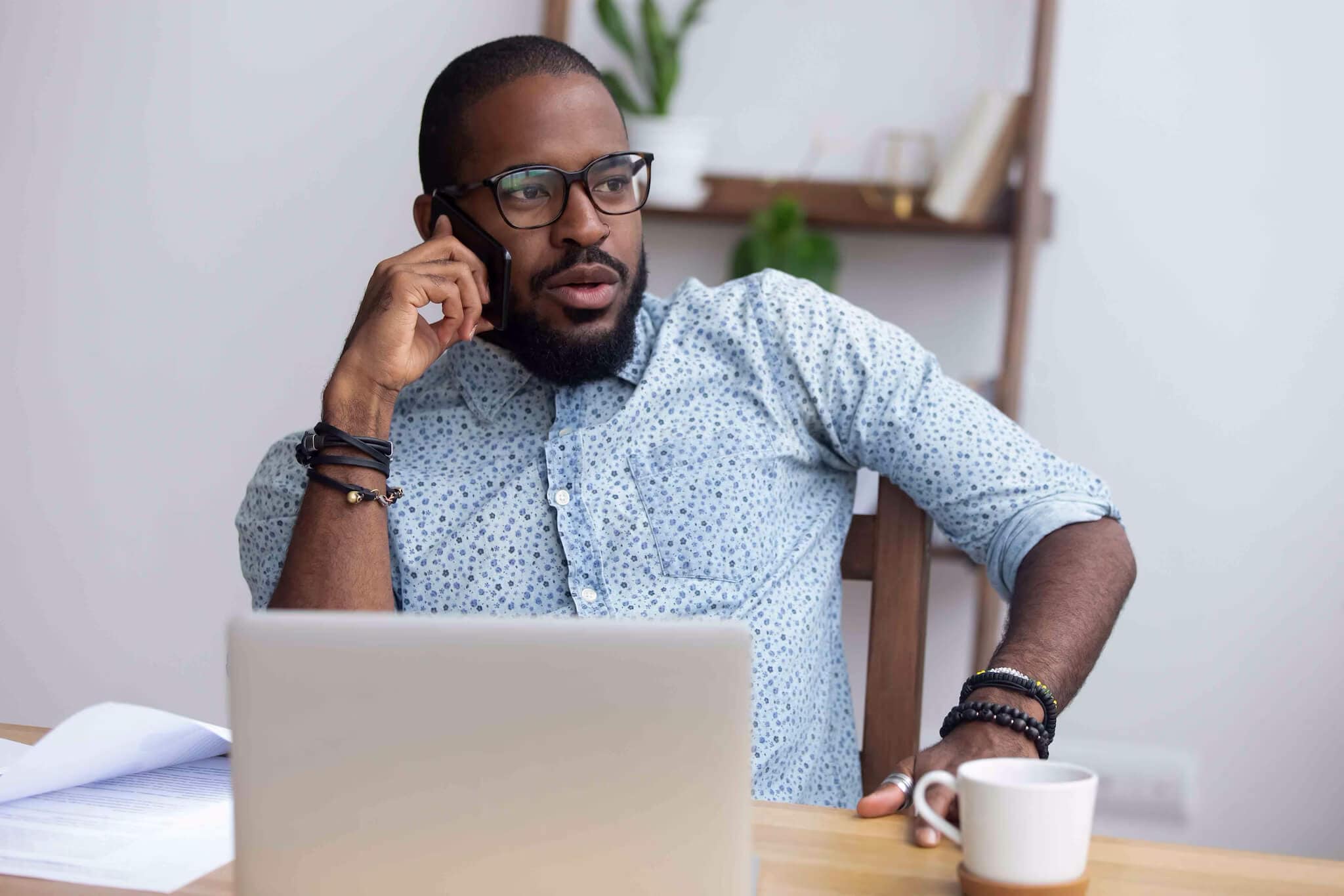 A man wearing glasses and a shirt is engaged in a phone conversation, emphasizing communication for fraud protection.