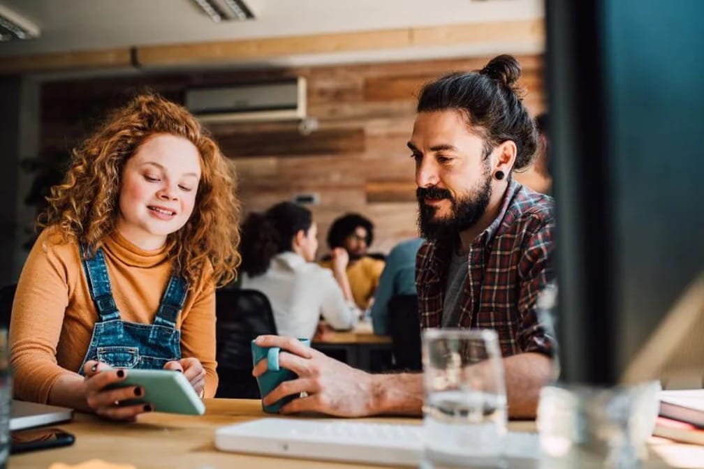 A woman and a man siting and watching credit building ways on a phone