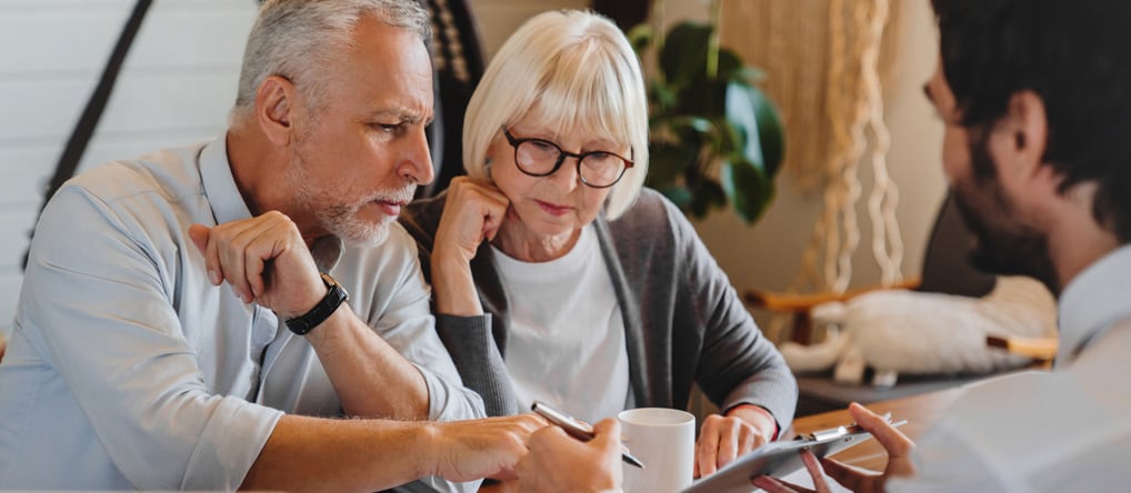Man showing older couple something on a clipboard