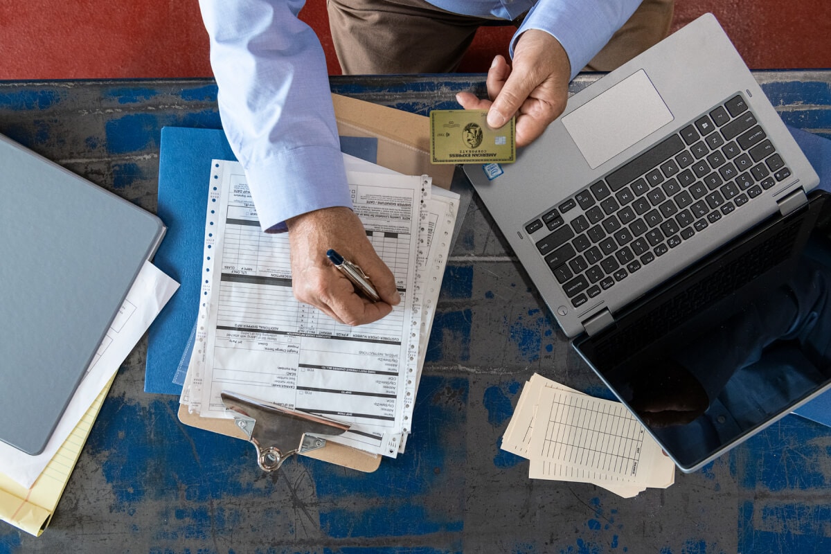 A person filling an application form and using a laptop.