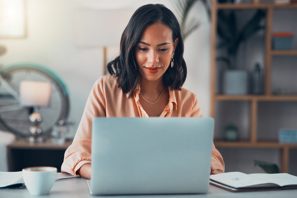 A person sitting on a desk and using a laptop.