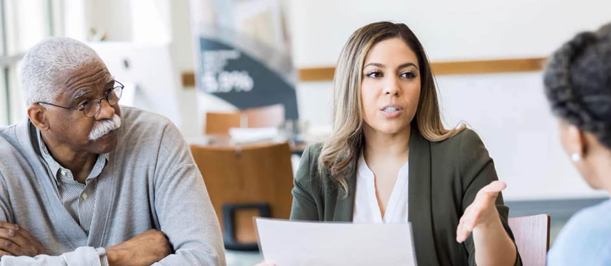 A woman engages in conversation with an older couple, discussing important topics related to debt and its implications after death.