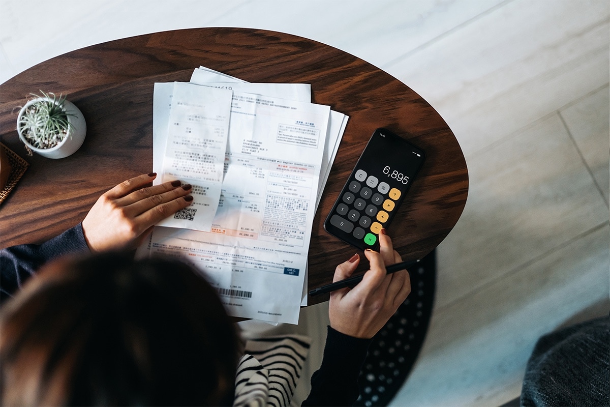 A close-up of a printed bank statement and calculator, showing someone manually looking over their statement