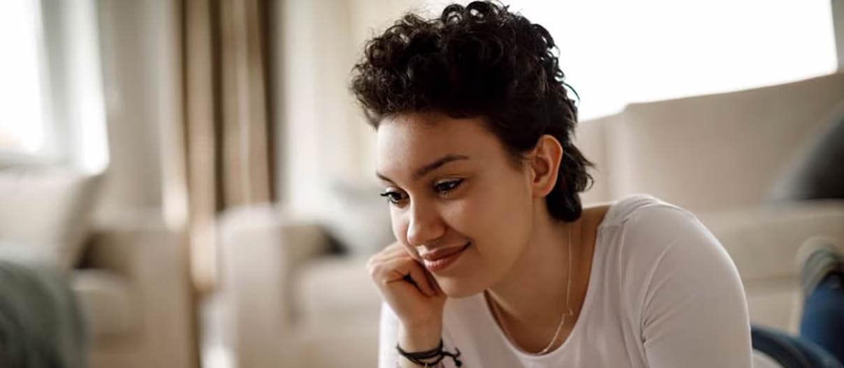 A woman lying on the floor, focused on her laptop as she checks her FICO score for financial insights.
