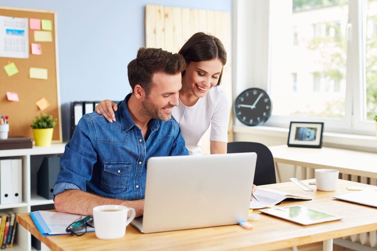 Millennial couple sitting at a table with paperwork or calendars in front of them.
