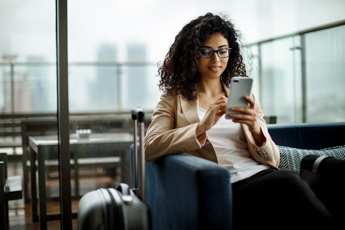 A woman in glasses engages with her phone, likely exploring details about wire transfers.
