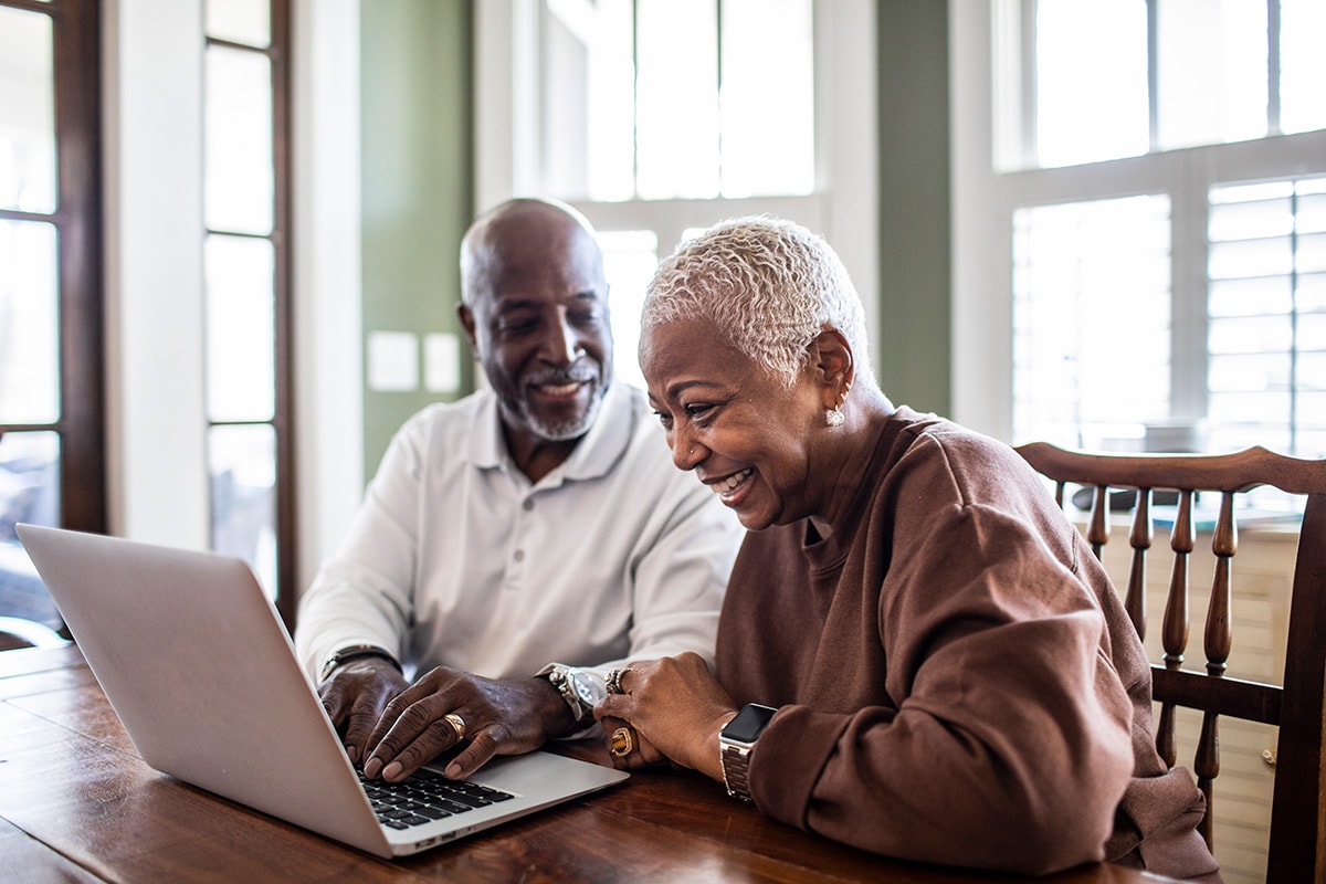 An older couple sits together, focused on a laptop, exploring information about Individual Retirement Accounts (IRAs).