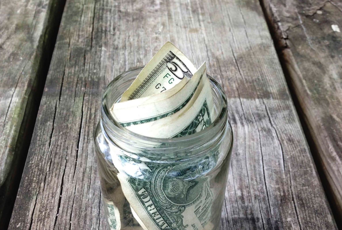 Jar of money, dollars and coins, on the bench 
