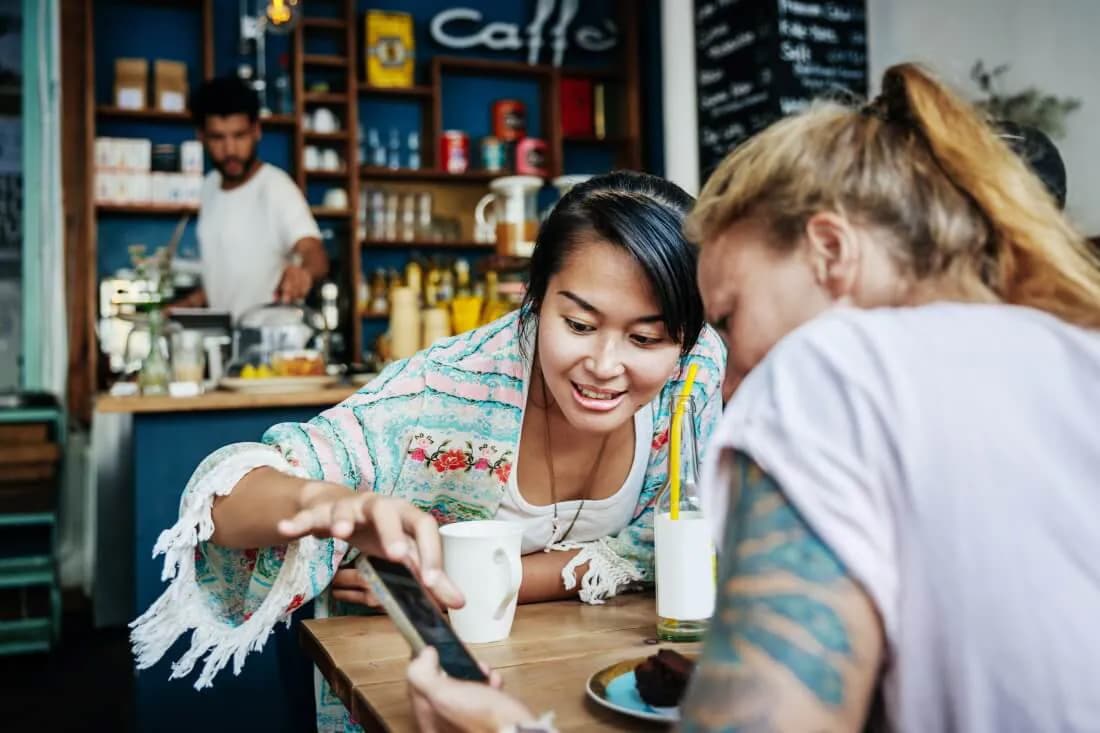 Two women in a cafe looking at a phone